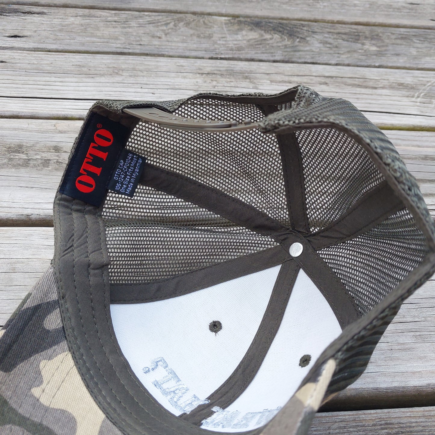 What Hat? embroidered on camo mesh trucker hat, under view